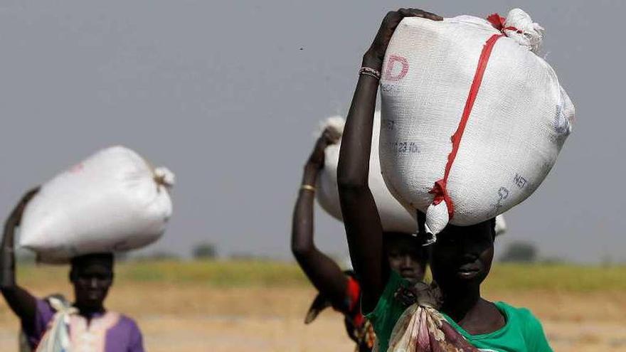 Mujeres de Sudán del Sur cargan sobre sus cabezas sacos de comida durante las hambrunas del pasado invierno.