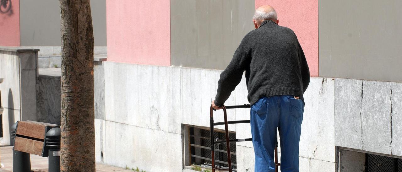 Un hombre pasea por Mieres con ayuda de un andador.