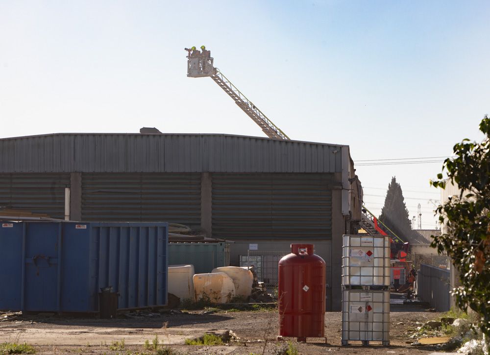 Los bomberos siguen trabajando en la nave del Port de Sagunt un día después del incendio