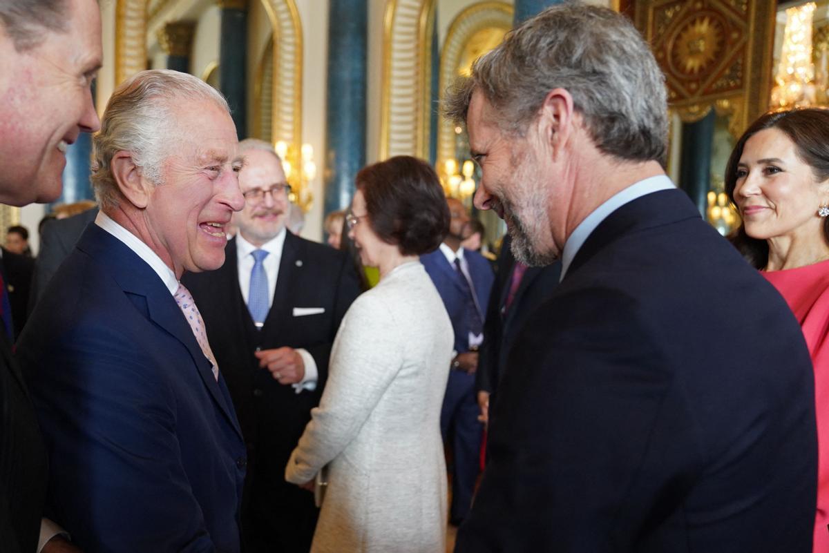 El rey Carlos III de Gran Bretaña (izquierda) habla con la princesa heredera María de Dinamarca (derecha) y el príncipe heredero Frederik de Dinamarca.