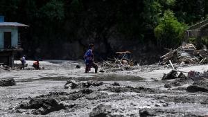 A woman wades along a road submerged in sludge and debris after flash floods in the Devighat area in Nepals Nuwakot district on August 27, 2026. Rescue teams rushed on August 27 to find more than 1,300 people missing on the Nepal-Tibet border in flash floods and landslides that killed at least 165 and swept away entire villages. (Photo by Prakash MATHEMA / AFP)