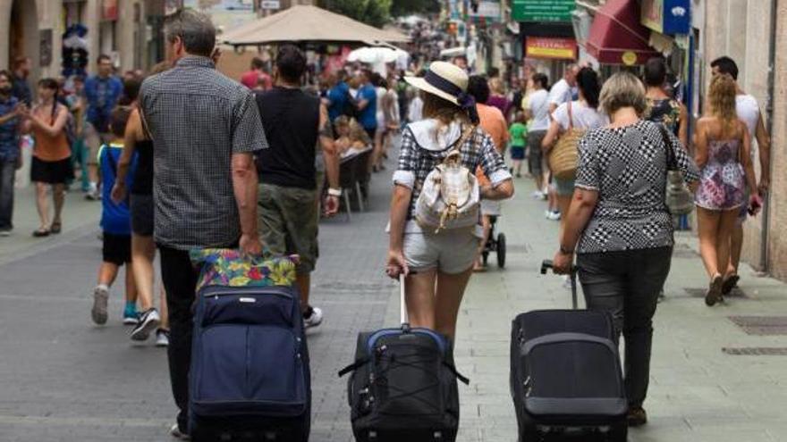 Turistas con su maleta por el centro de Palma, donde hoteles y apartamentos están llenos.