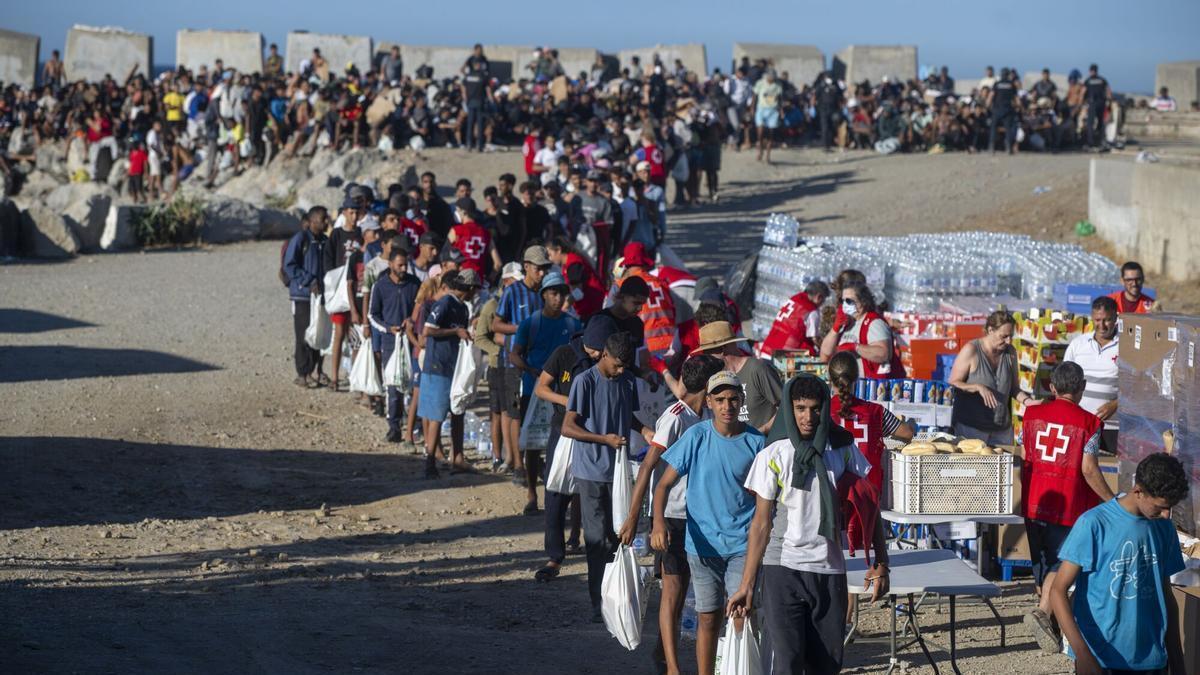 Miembros de la Cruz Roja reparten comida a los inmigrantes en una playa de Ceuta.