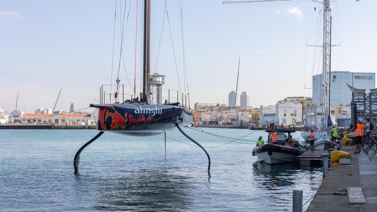 Los operarios de Alinghi Red Bull Racing levantan con una grúa el AC75 de las aguas del Port Vell para guardarlo en su nueva base definitiva.
