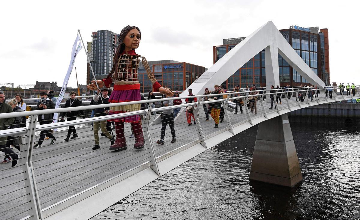 cruzando el puente Tradeston, sobre el río Clyde, en Glasgow. Un borrador del texto en la cumbre climática COP26 instó a los países a impulsar sus objetivos de reducción de emisiones para 2022, tres años antes de lo programado. Los datos mostraron que el mundo estaba muy lejos de limitar el calentamiento a 1,5 °C