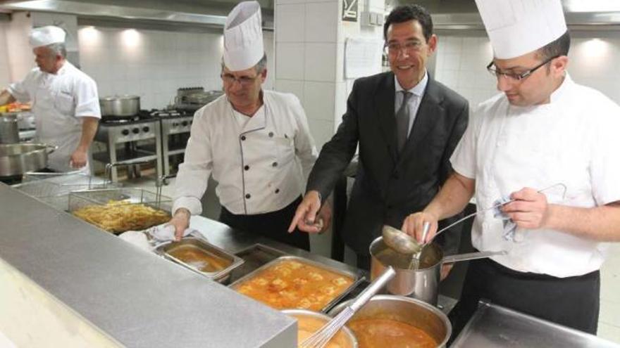 El director del Regente, entre varios cocineros del establecimiento, mostrando algunos de los platos calientes que preparan cada día.