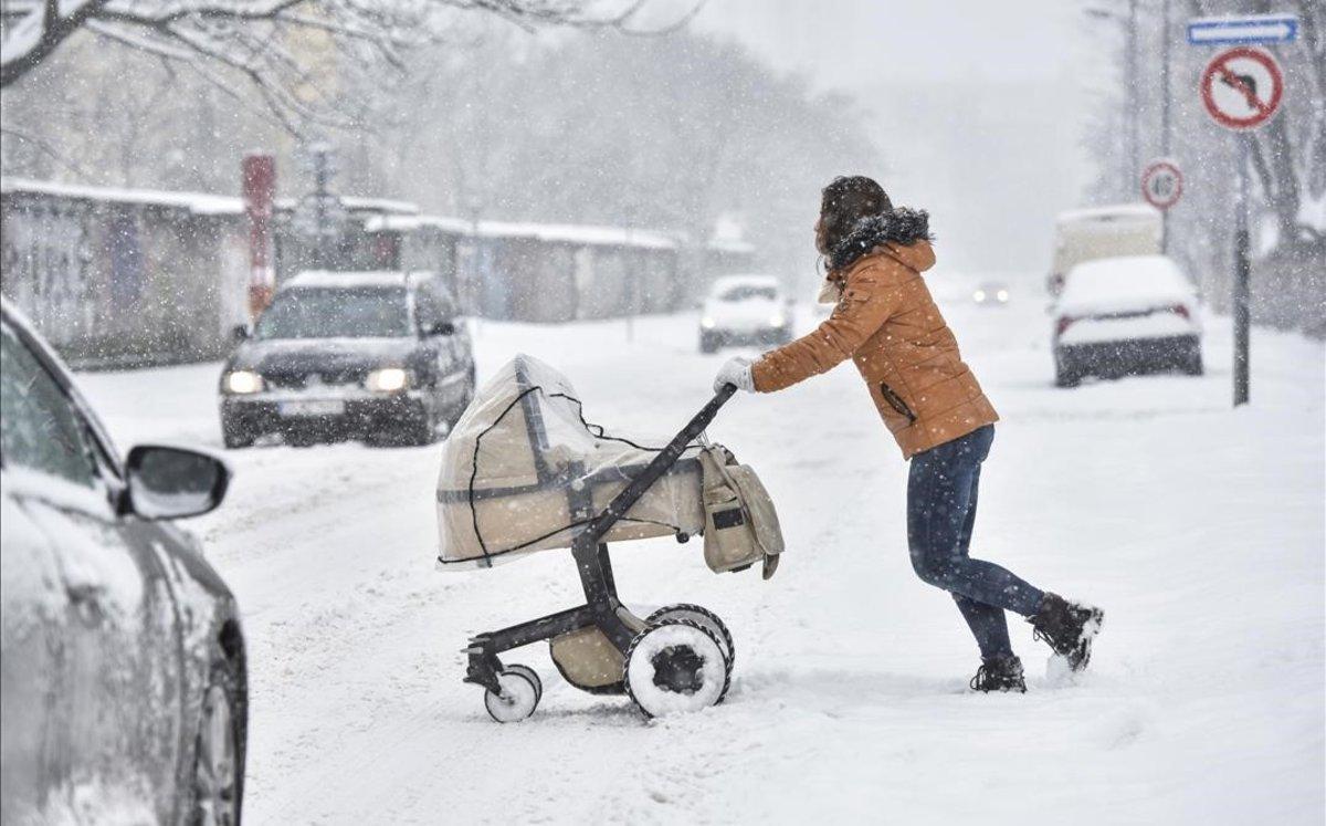 Una mujer y su bebé en una calle de Bratislava, Eslovaquia, durante una fuerte nevada.