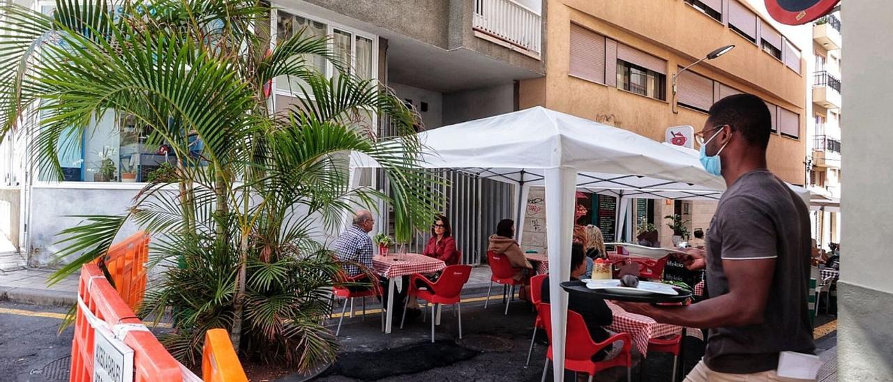 Un trabajador atiende una terraza en una calle de Santa Cruz de Tenerife.