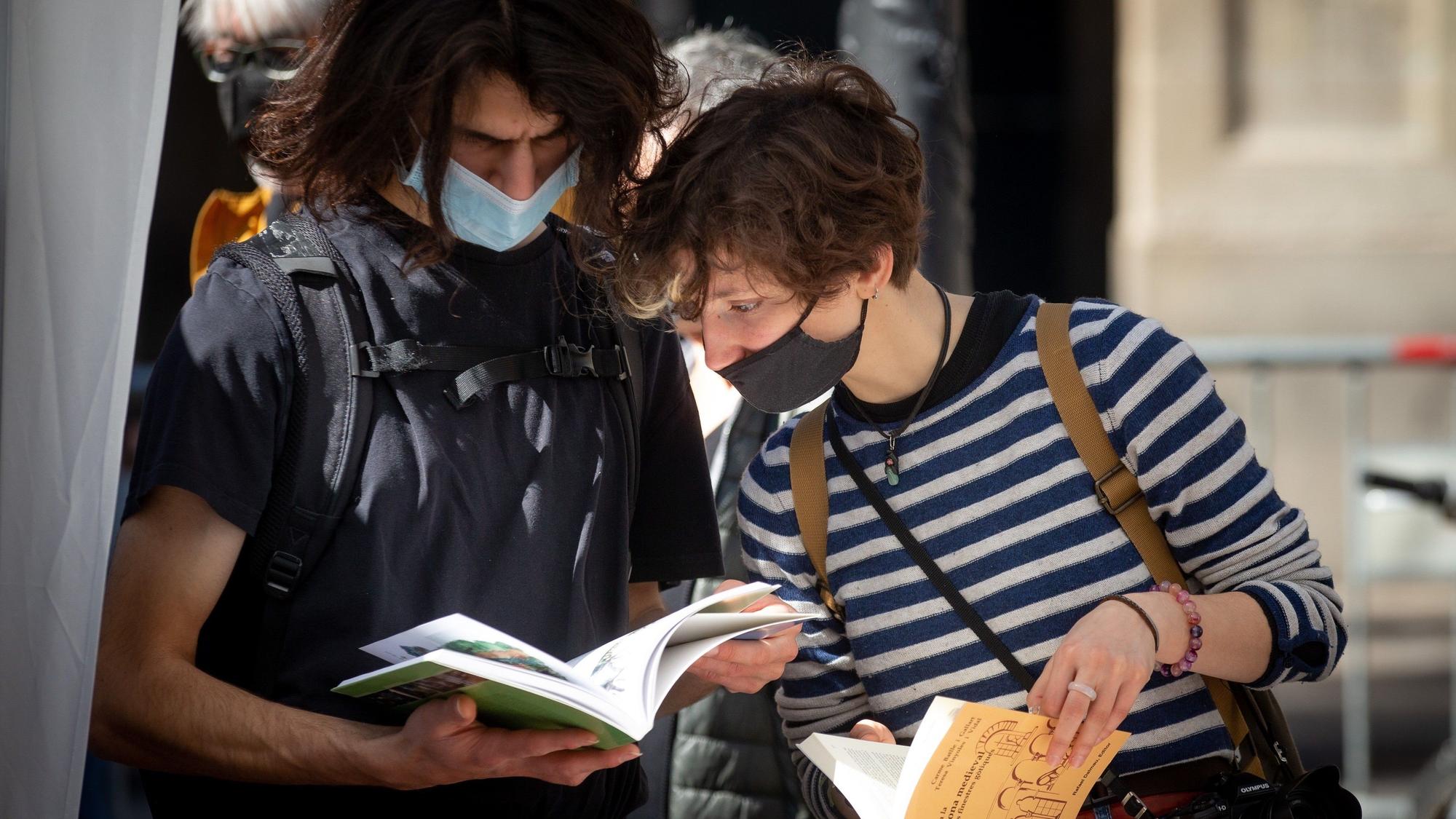 Dos personas miran libros en la 'diada' de Sant Jordi, en Barcelona