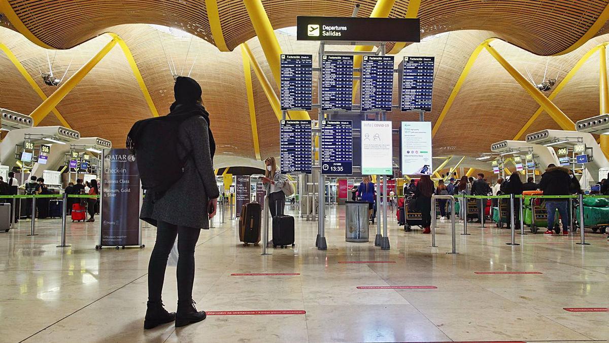 Una pasajera comprueba horarios de aviones en las pantallas de información de Barajas. |   // EFE