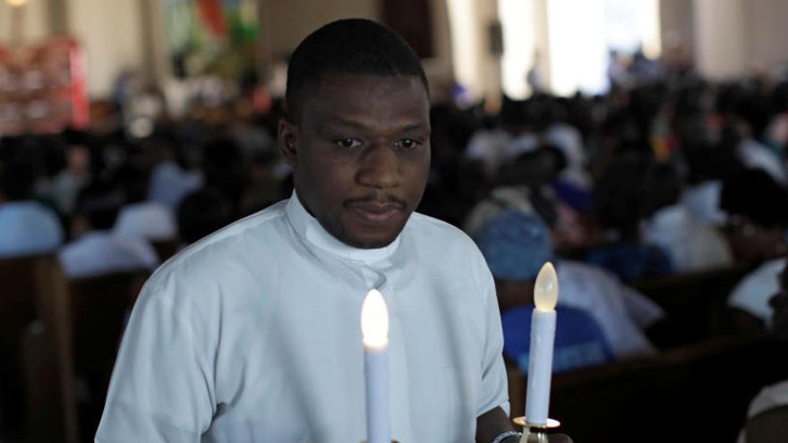 Un sacerdote lleva velas por el décimo aniversario del seísmo.