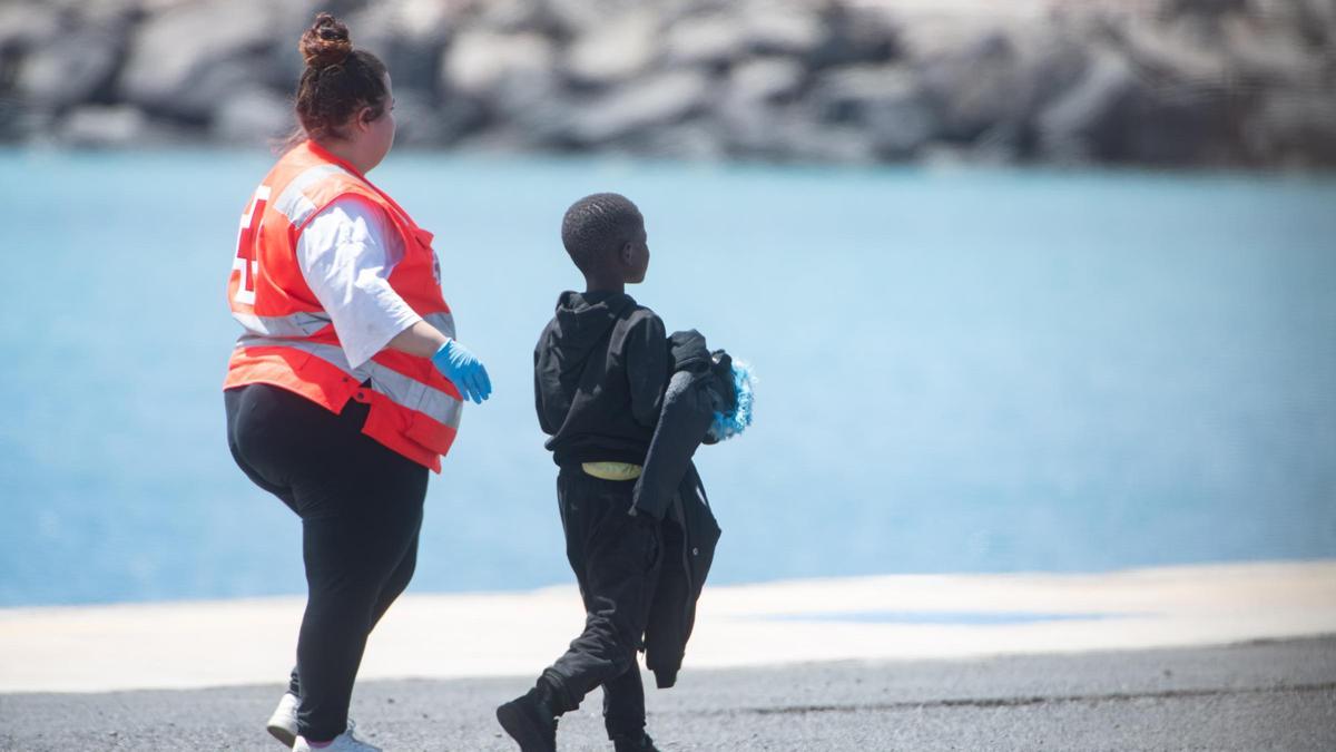 Un menor migrante junto a una voluntaria de Cruz Roja, en el muelle de Puerto del Rosario, en Fuertevenura.