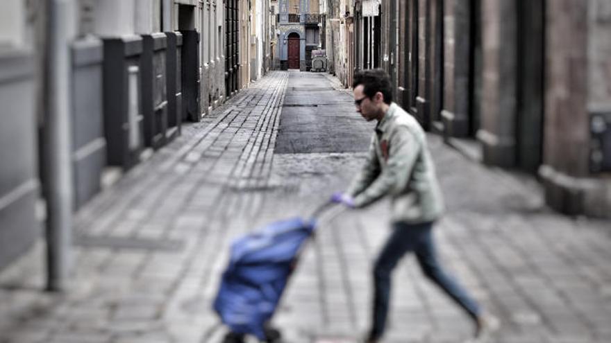 Un ciudadano atraviesa una solitaria calle de la capital tinerfeña con un carrito de la compra.