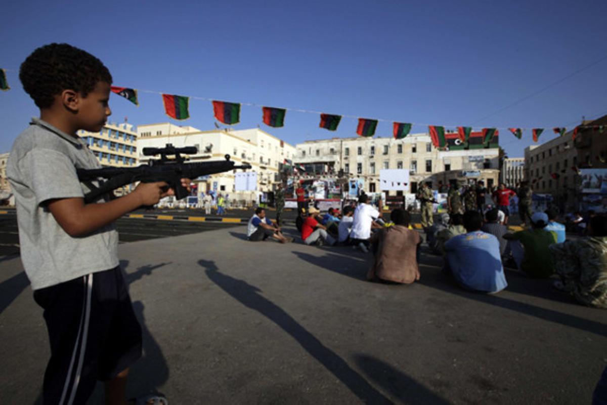 Un nen libi apunta amb un fusell de joguina els rebels concentrats a la plaça Tahrir de Bengasi (Líbia).