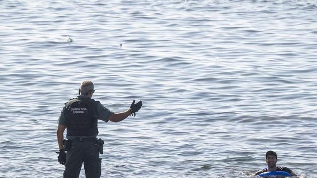 Un guardia civil adverteix una persona que neda al mar intentant entrar a Ceuta, ahir.   | MARCOS MORENO / EUROPA PRESS