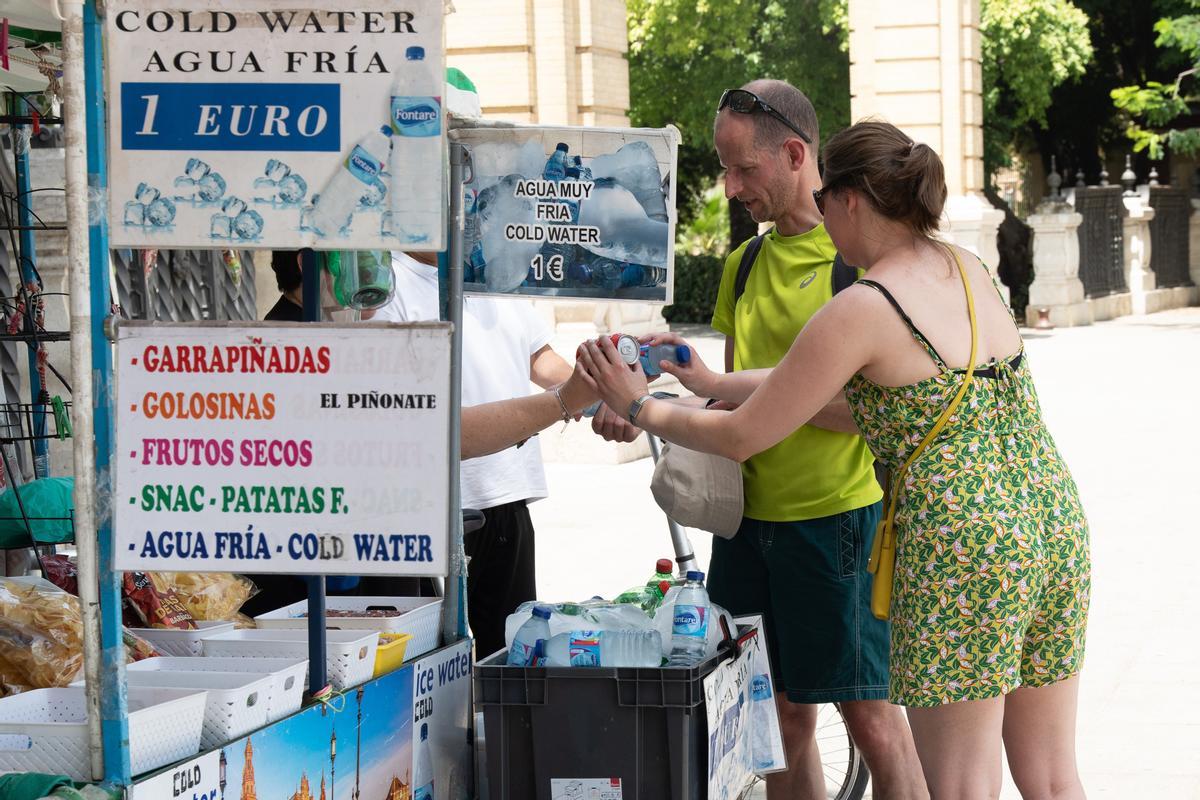 Unos turistas compran agua en un puesto callejero de la ciudad. Las altas temperaturas  siguen afectando a Andalucía en esta segunda ola de calor del verano.