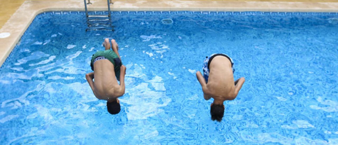 Dos jóvenes se lanzan al agua haciendo acrobacias en una piscina sin socorrista de la Playa de San Juan.