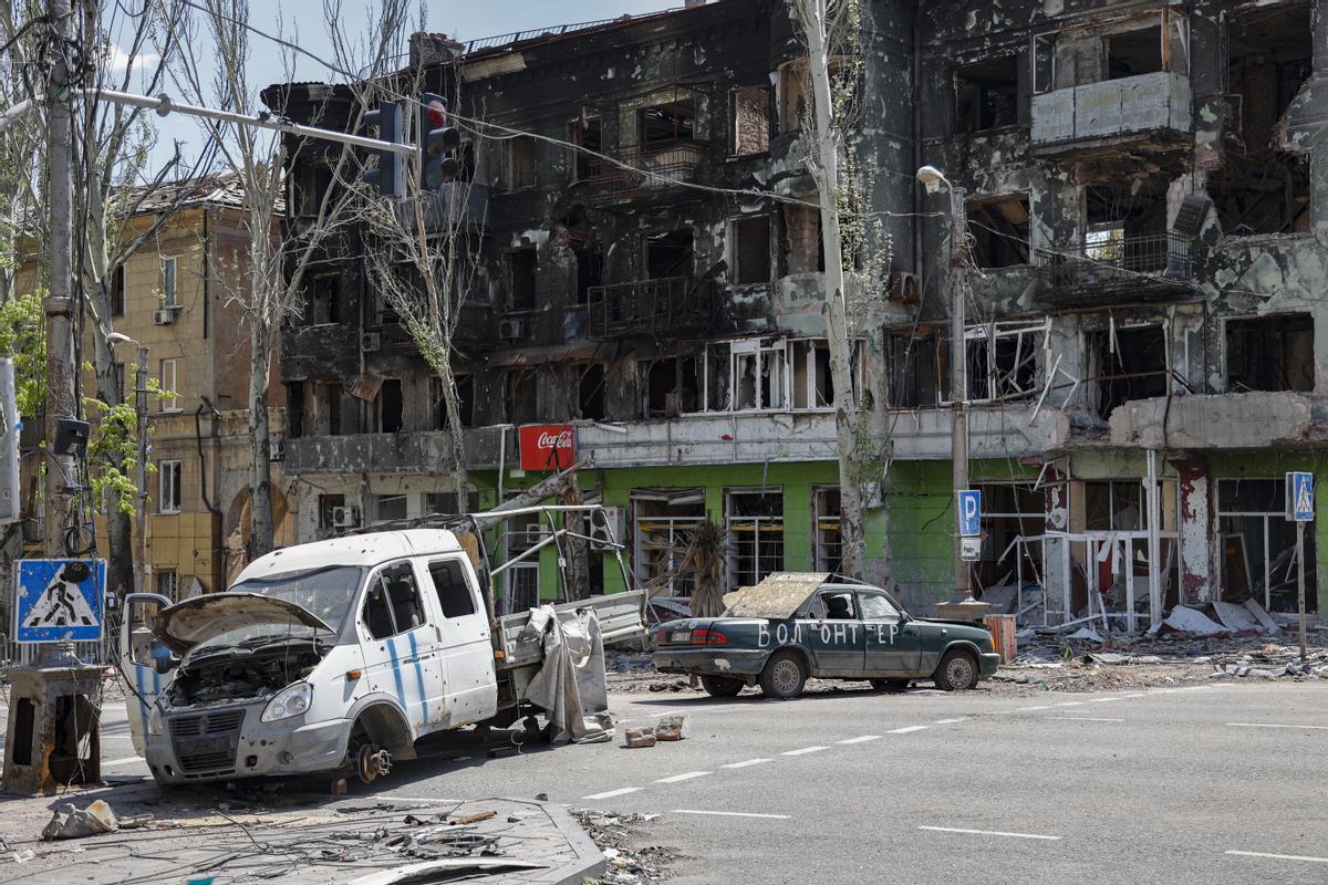 Autos destruidos bloquean una calle durante las celebraciones del Día de la Victoria en Mariupol, Ucrania