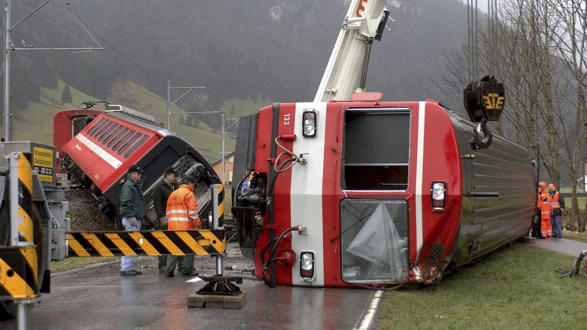 Trabajadores de los servicios de rescate inspeccionan los vagones de un tren regional  de Suiza después de su descarrilamiento.