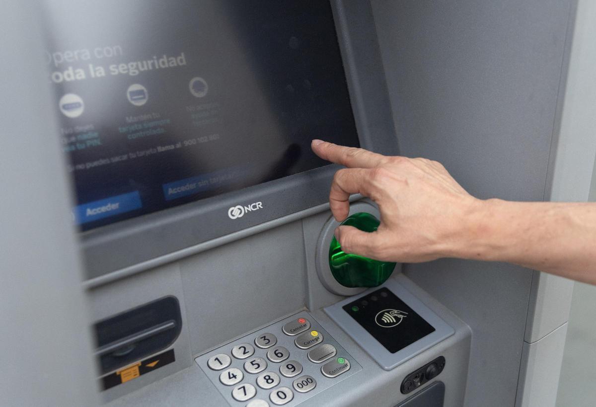 Una persona saca dinero de un cajero automático en una imagen de archivo.