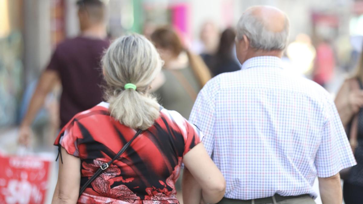 Una pareja de jubilados pasea del brazo por una calle de Madrid.