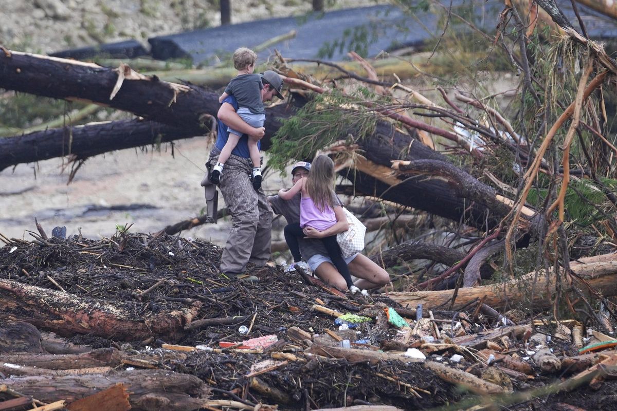 Una pareja con sus hijos en brazos atraviesan una zona afectada por la crecida del río Guadalupe en Texas, este sábado.