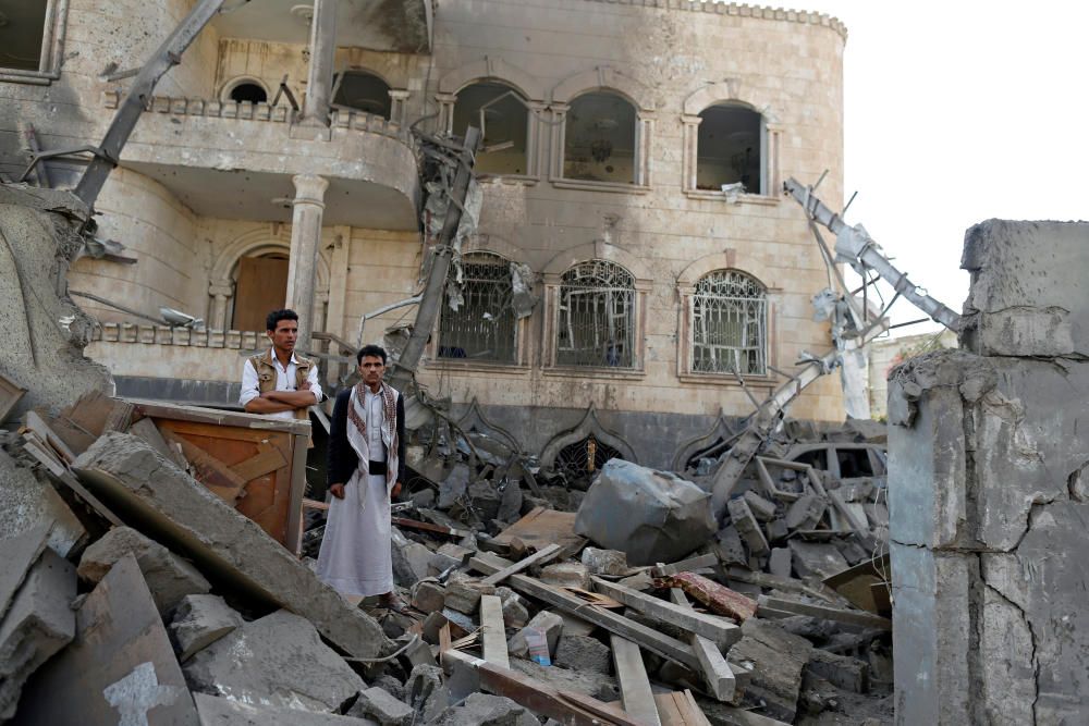 People stand on the rubble of a house destroyed ...