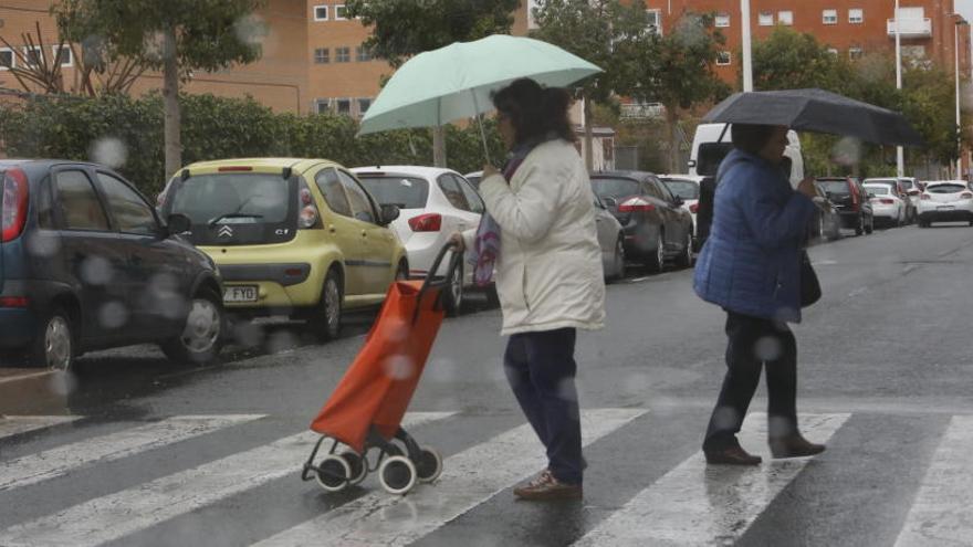 Vecinos con paraguas esta mañana en Elche.