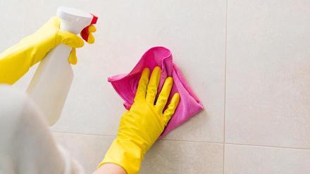 Mujer haciendo limpieza de baño en casa, pared de azulejos de