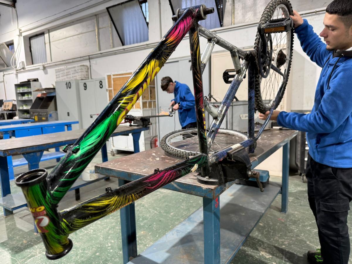 Dos alumnos trabajan con sendas bicicletas en el taller formativo.