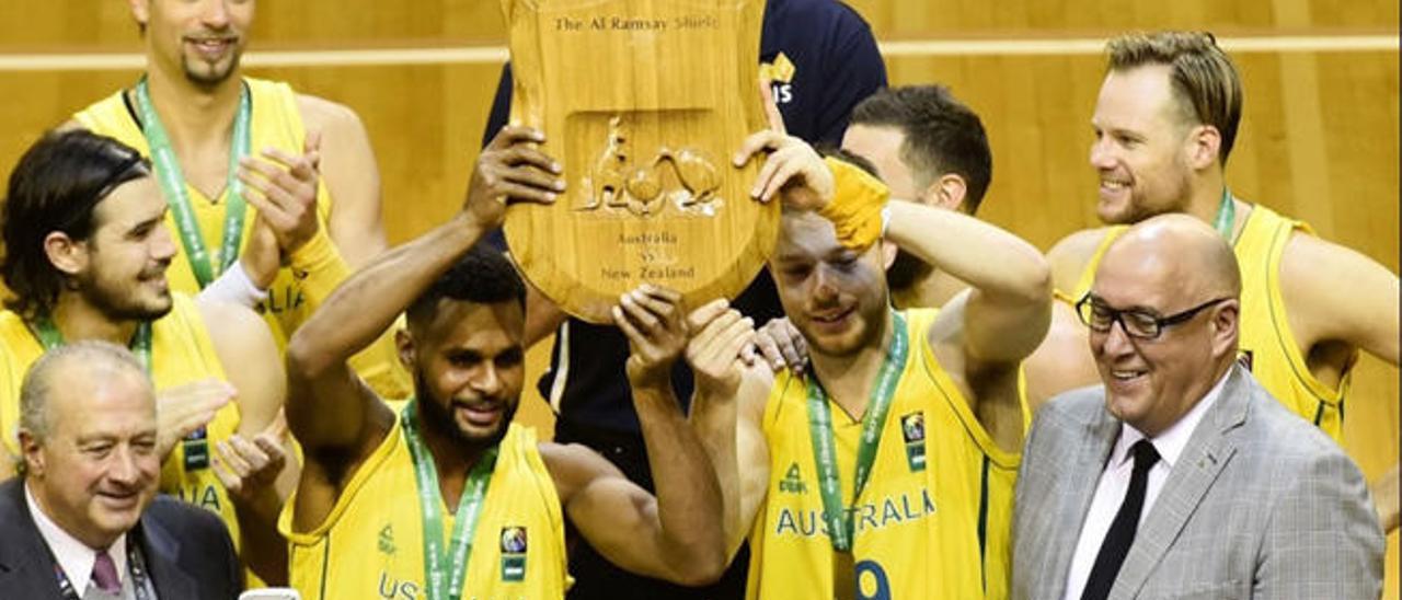 Patty Mills (izq.) y Matthew Dellavedova (dcha.) sostienen el trofeo de campeones con Newley a la derecha.