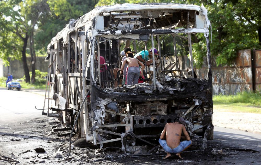 People remove the remains of a burned bus in ...
