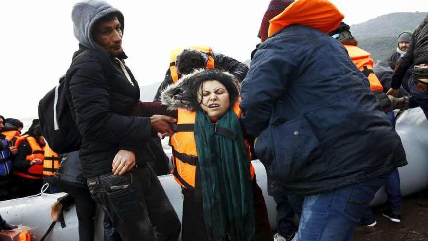 Una refugiada iraquí es ayudada al desembarcar de un &quot;dinghy&quot; en una playa de Lesbos. // Reuters