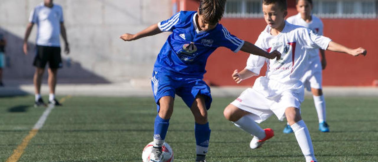 Arriba, las formaciones de los alevines del Lomo Blanco y San Fernando. A un lado, Gabriel, con el balón, trata de eludir la entrada de su adversario.