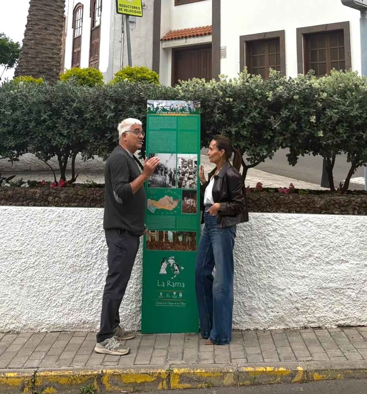 Valentín Barroso y María del Carmen Rosario junto a uno de los carteles explicativos de la fiesta de La Rama de Agaete.