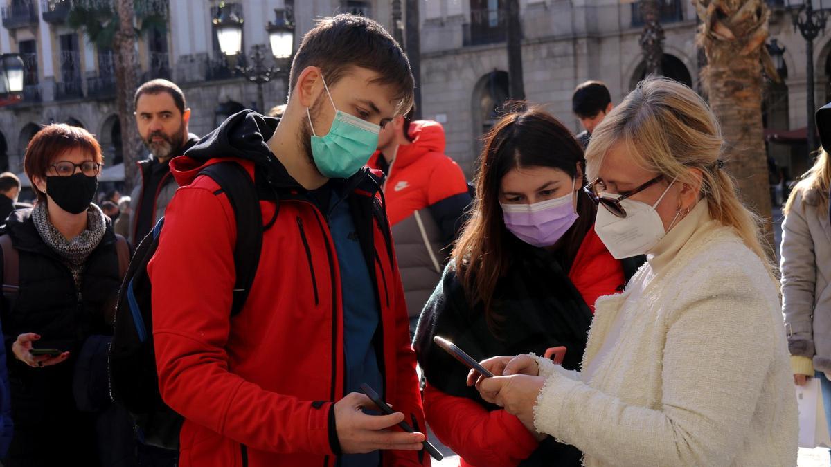 Pla mitjà d&#039;una parella ensenyant el certificat covid per accedir a un restaurant de la plaça Reial de Barcelona