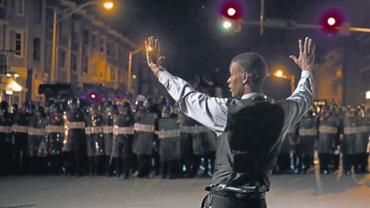 Un joven se encara a la policía durante el toque de queda en Baltimore.