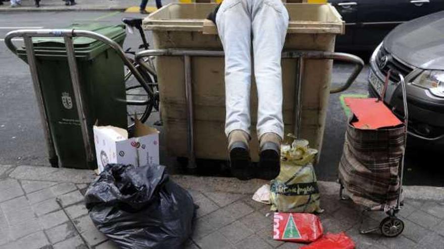 Un hombre rebusca en un contenedor situado en un céntrica calle de la ciudad. / carlos pardellas