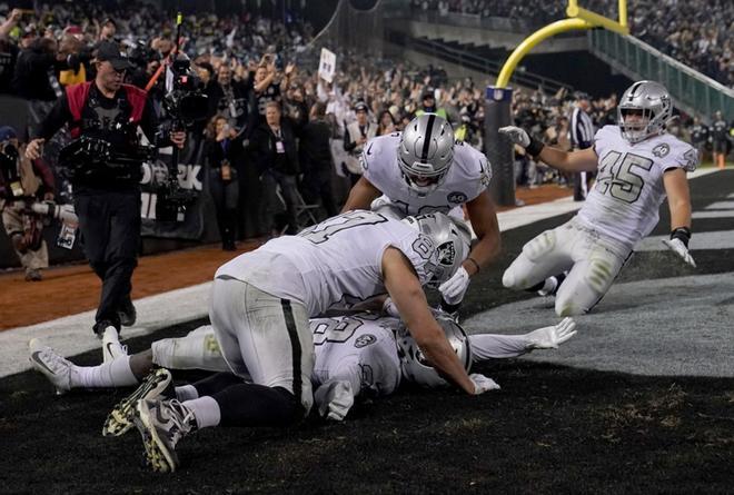 Josh Jacobs # 28 de los Oakland Raiders celebra con sus compañeros de equipo después de anotar en un touchdown de 18 yardas al final del último cuarto contra los Chargers de Los Ángeles en el RingCentral Coliseum.