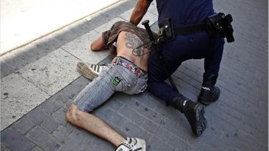 Un policia immobilitza un dels indignats concentrats davant de les Corts valencianes.
