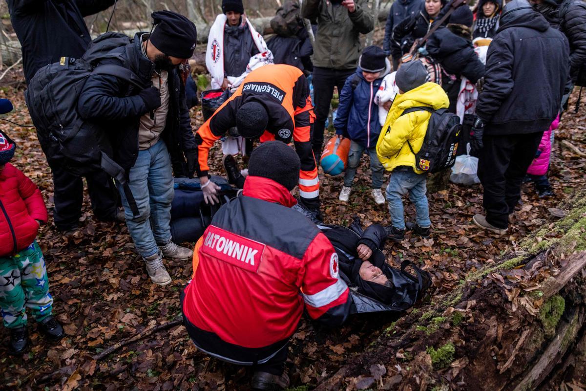 WOJTEK RADWANSKIA1-131701766.jpgTOPSHOT - Paramedics prepare to transport an elderly woman and member of a Kurdish family from Dohuk in Iraq as the border guard patrol prepares to take the family to the town of Narewka, Poland, near the Polish-Belarus border on November 9, 2021. - The three-generation family of 16 members with seven minors, including the youngest who is five months old, spent about 20 days in the forest and was pushed back to Belarus eight times. They claim they were beaten and frightened with dogs by Belarusian soldiers. (Photo by Wojtek RADWANSKI / AFP)