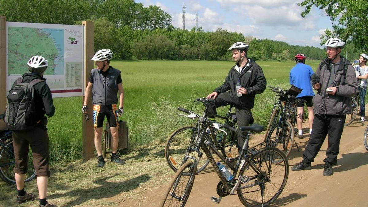 Uns ciclistes miren un panell informatiu en una de les vies verdes gironines
