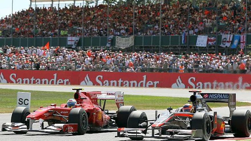 Fernando Alonso adelanta al indio Karum Chandhok, de Hispania, durante el Gran Premio de Gran Bretaña.