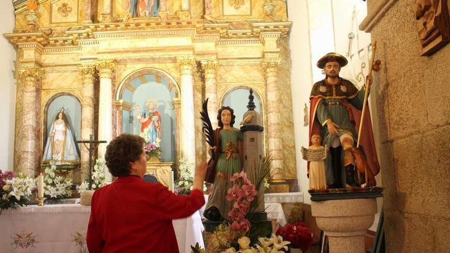 Unha muller diante da imaxe da santa e exterior da igrexa de Cumeiro. // Daniel González Alén