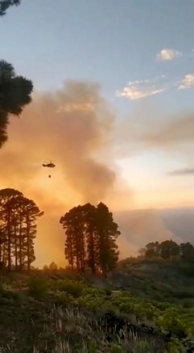 A firefighting helicopter is seen as wildfire ...