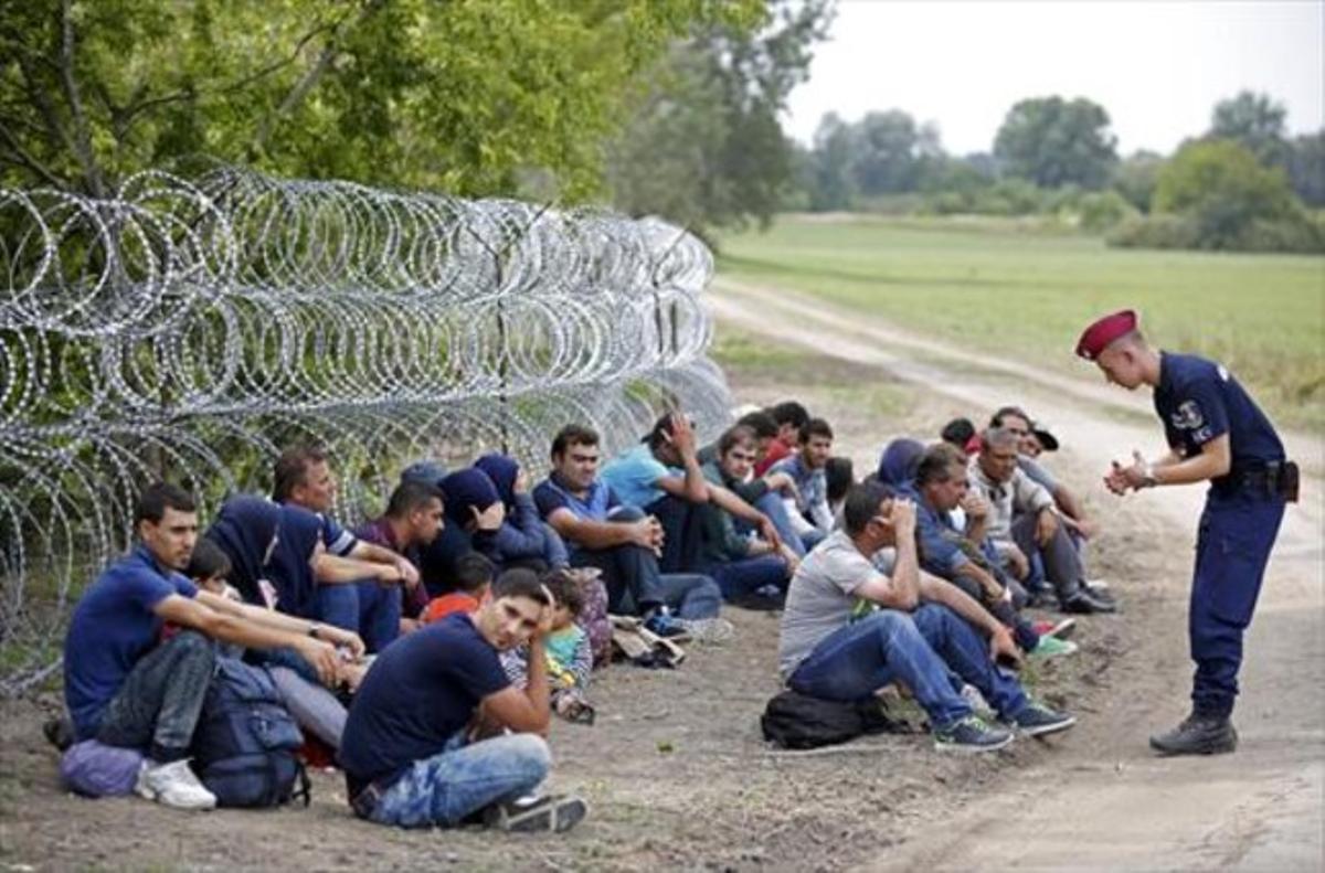 Un policía húngaro con varios detenidos tras cruzar desde Serbia.