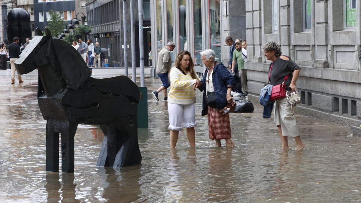 Una impresionante tromba de agua con fuertes rachas de viento inunda la calle Uría de Oviedo y complica la circulación en el centro