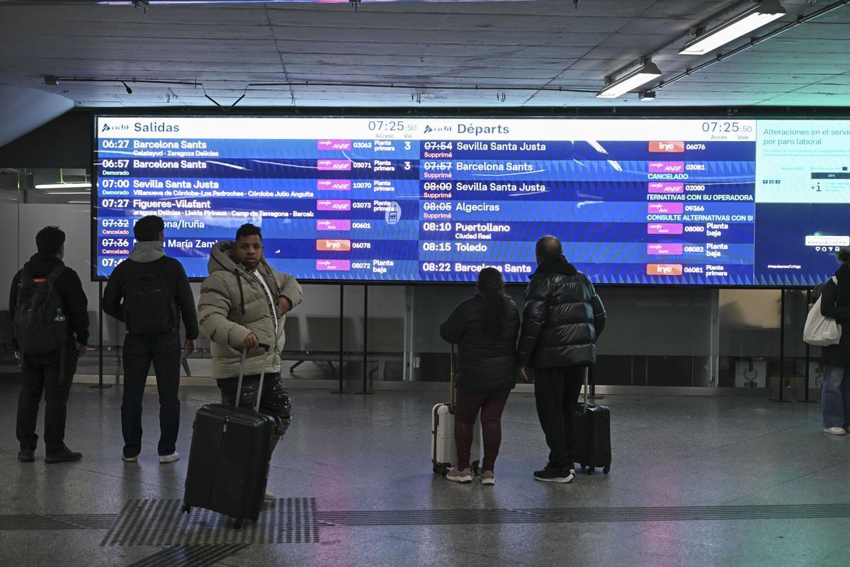 Viajeros afectados por la huelga de trabajadores feroviarios consultan los horarios de los trenes de alta velocidad en la estación de atocha de Madrid este lunes.
