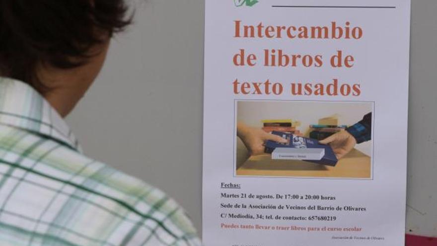 Un joven observa el cartel que anuncia el mercadillo de libros de texto en el barrio de Olivares.