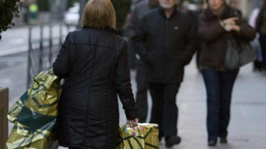 Una mujer cargada con bolsas de la compra.